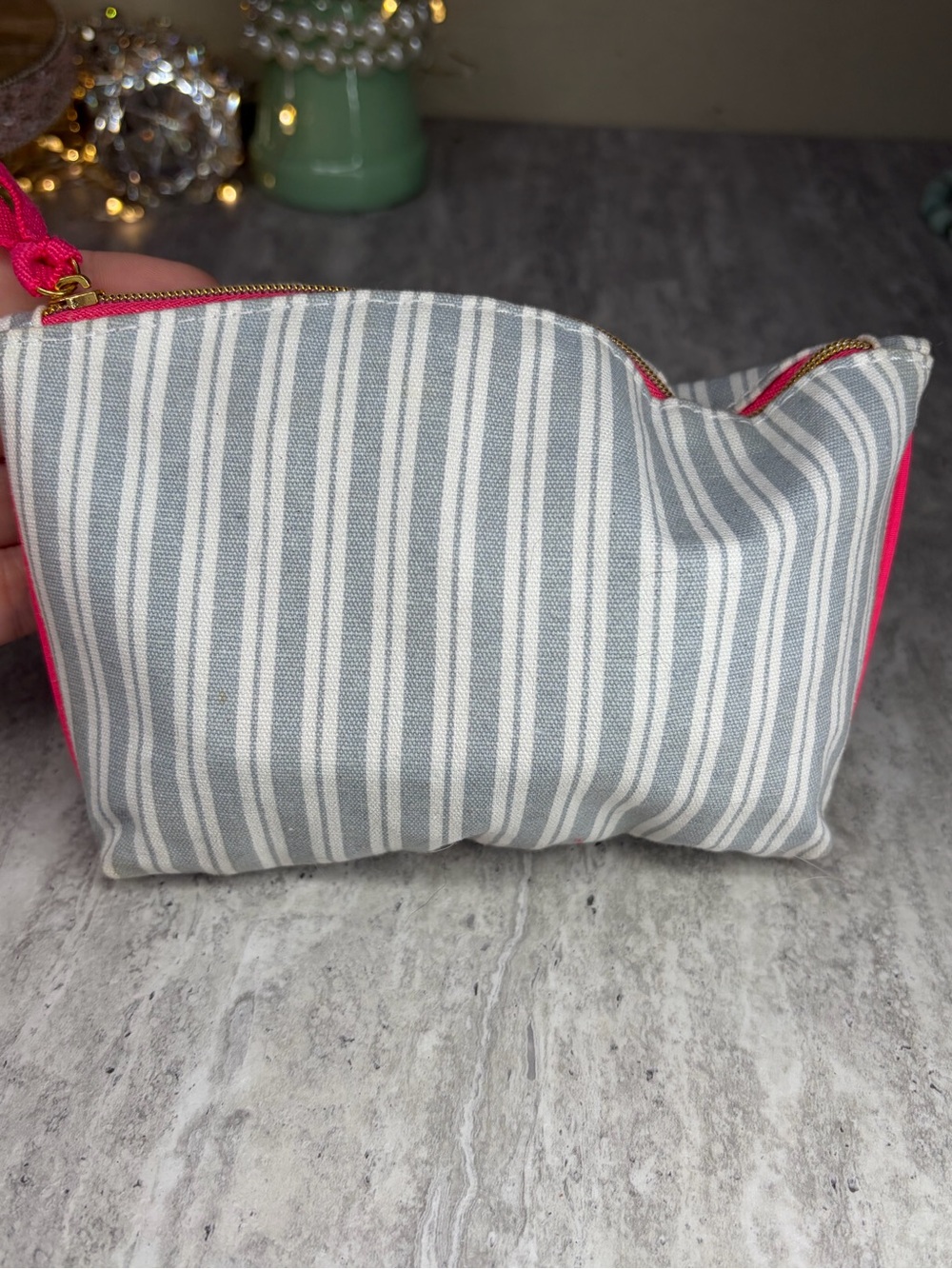 Striped Ipsy makeup cosmetic bag filled with wearable jewelry